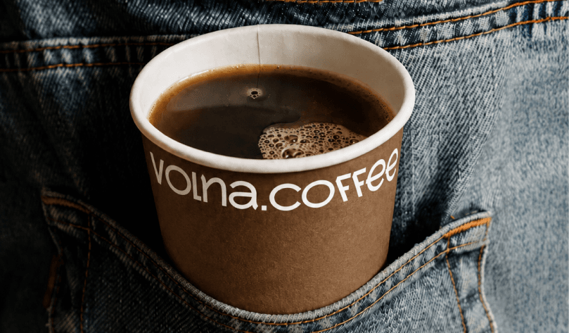 Брендированный стакан навынос «volna.coffee» в заднем кармане джинсов